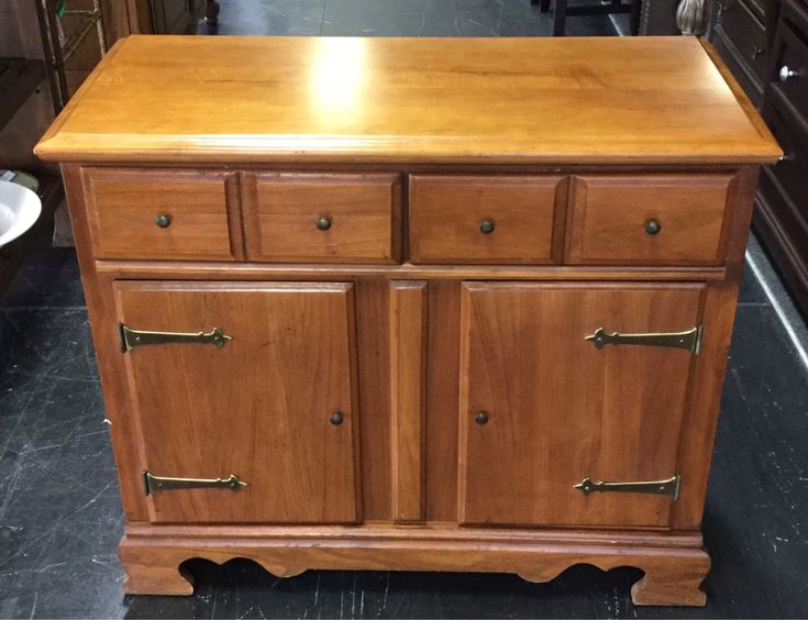 a wooden cabinet with brass handles and knobs on the top, in a store