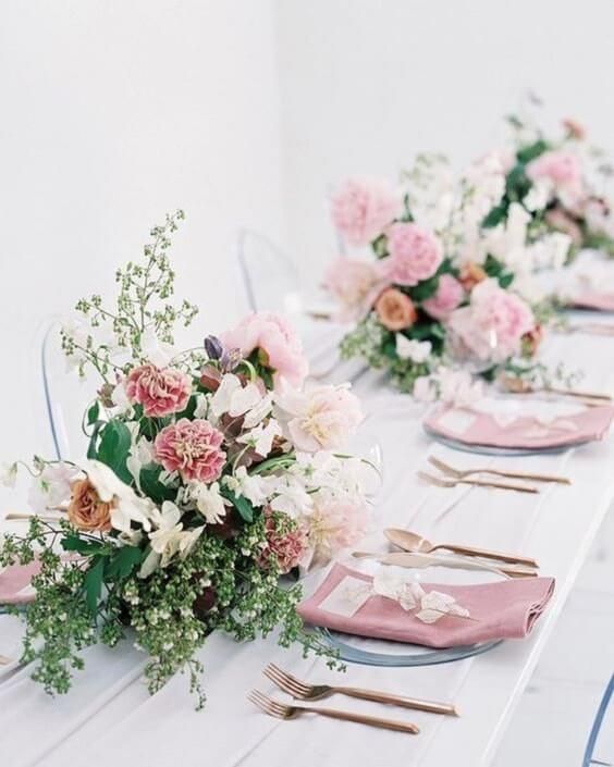 the table is set with pink napkins and floral centerpieces, along with silverware