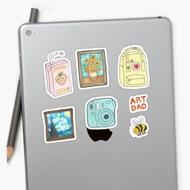 a laptop with stickers on it sitting next to a pencil