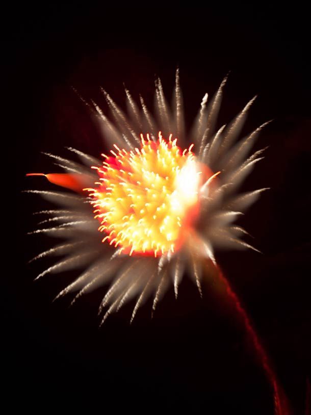 a red and white firework in the night sky with bright light coming from it