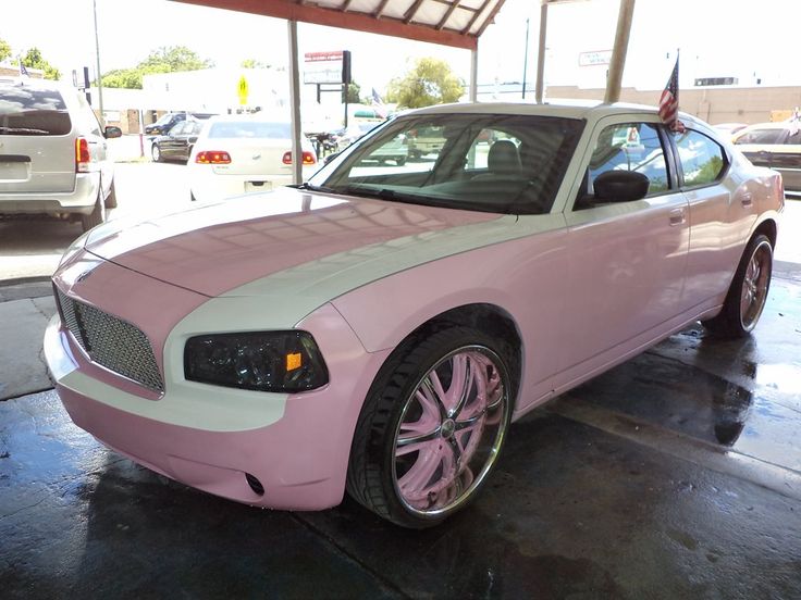 a pink and white car parked in a parking lot