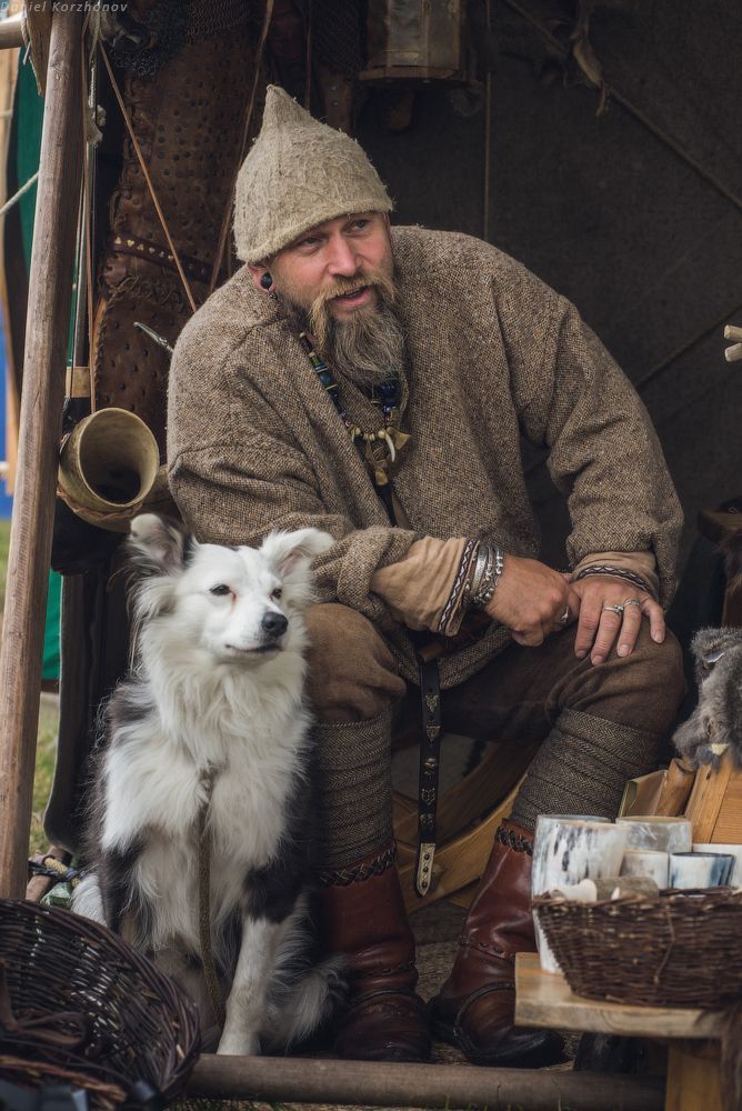 a man sitting on the ground with his dog next to him and many other items