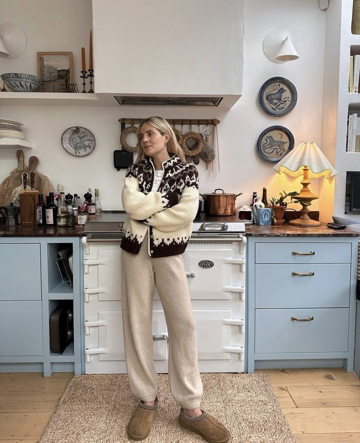 a woman standing in a kitchen with her arms crossed