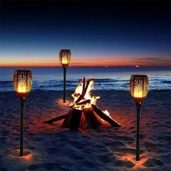 three torches sitting on top of a sandy beach