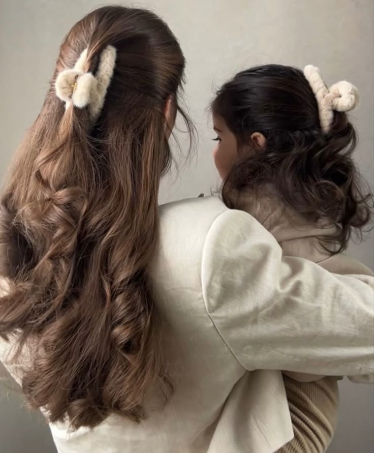 two girls with long hair and bows on their heads are facing each other in opposite directions