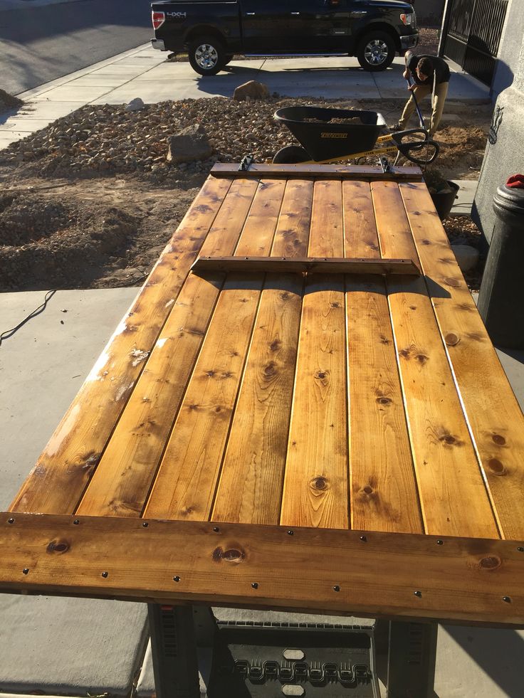 a wooden picnic table sitting on the side of a road next to a black truck