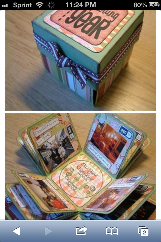 an open box sitting on top of a wooden table next to other boxes with pictures inside