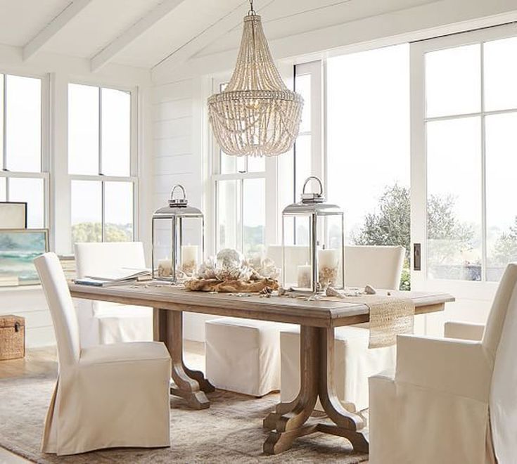 a dining room table with chairs and a chandelier hanging from it's ceiling