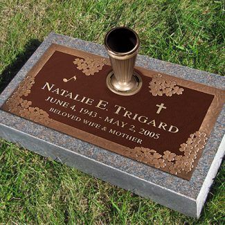 a memorial in the grass with a cup on it's base and a name plate