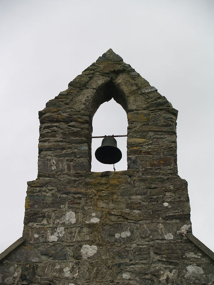 an old stone building with a bell in the middle and a window on one side