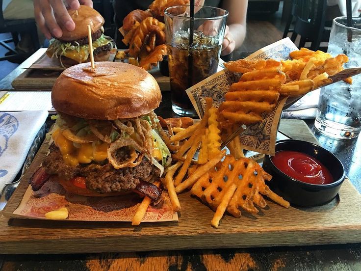 a large cheeseburger with fries and ketchup is on a wooden tray