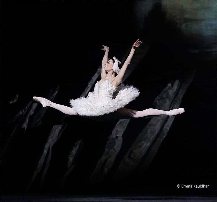 a ballerina is in the air with her arms outstretched and legs spread out, while she