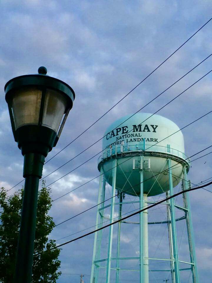 a large water tower next to a street light and lamp post on a cloudy day