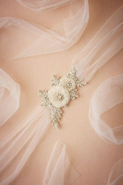 a bridal brooch with white flowers on it's lapel and veil