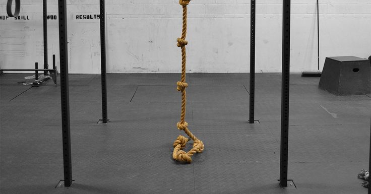 a rope is tied up in the middle of a room with four black poles and two white brick walls