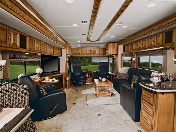 the interior of an rv with wood cabinets and black leather chairs in front of it