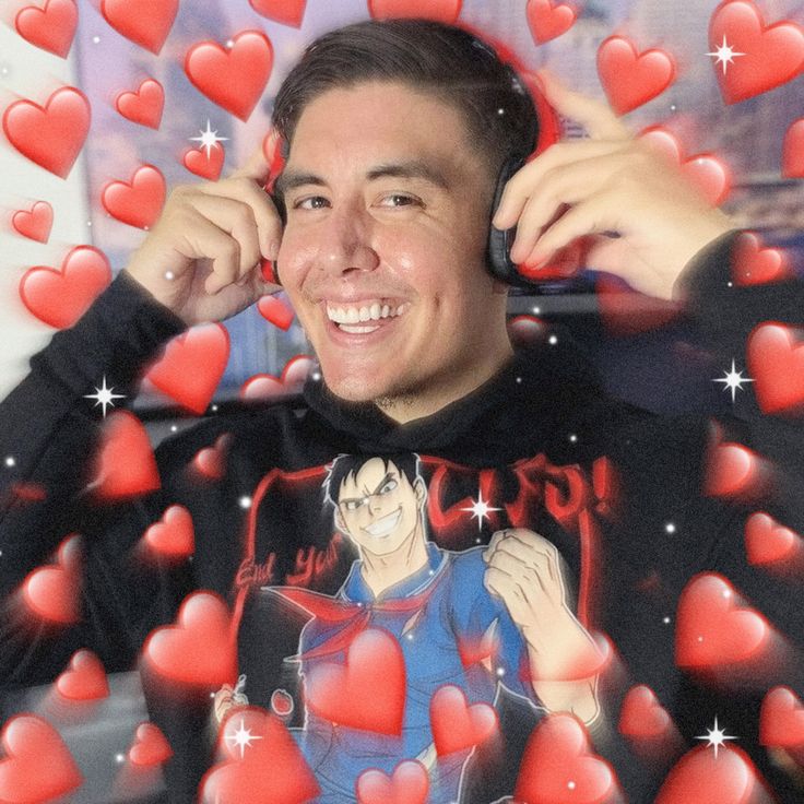 a man is smiling while holding his head in front of heart shaped red hearts on the wall