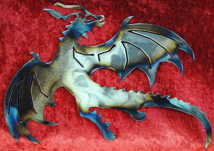 a metal dragon sitting on top of a red velvet surface with its wings spread out