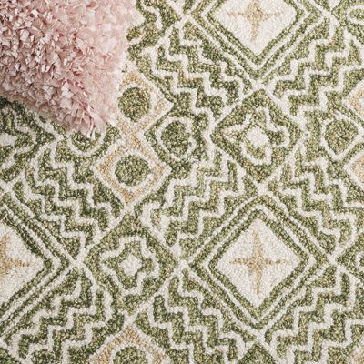 a pink pillow sitting on top of a green and white rug