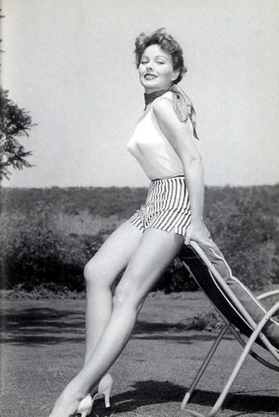 a black and white photo of a woman in a bathing suit sitting on a chair