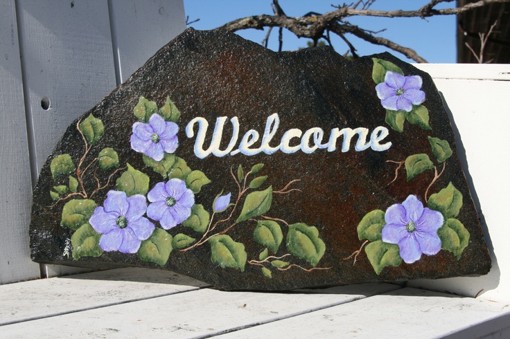 a rock with flowers painted on it that says welcome