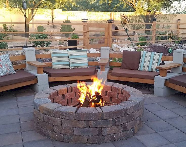 a fire pit surrounded by wooden benches and pillows