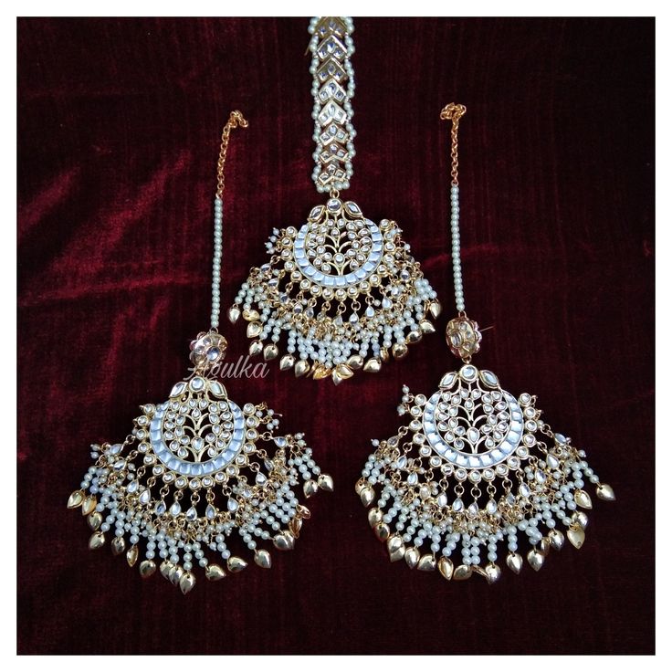 *PRODUCT DETAIL* *Material: Brass *Plating: Gold Plated *Stone: Semi Precious Kundan & Pearls *DIMENSIONS * *Tikka: Weight: 71 gm, Length: 4 Inches, Width: 2.6 Inches, Top Chain Length: 3.12 Inches *Earrings: Weight: 59 gm each, Length: 4.14 Inches, Width: 2.08 Inches *ABOUT PRODUCT* *Beautiful Jadau Kundan Maang Tikka in gold plating and pearl detailing. *Style Tip : A piece to Bring out your Eye for Exclusivity. *DISCLAIMER* *Product & color may slightly vary due to photographic lighti White Latkans Tikka For Ceremonial Events, Traditional Bridal Accessories For Festivals And Celebrations, Meenakari Chandbali Bridal Earrings, Heavy Chandbali Tikka For Wedding, Temple Jewelry Stone Work Danglers For Wedding, Tilla Chandbali Bridal Sets For Celebration, White Chandbali Bridal Sets For Ceremonies, Festive Bridal Meenakari Earrings For Marriage, Traditional Silver Bridal Accessories For Marriage