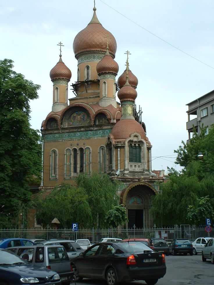 an old church with two towers and crosses on it's roof, surrounded by trees