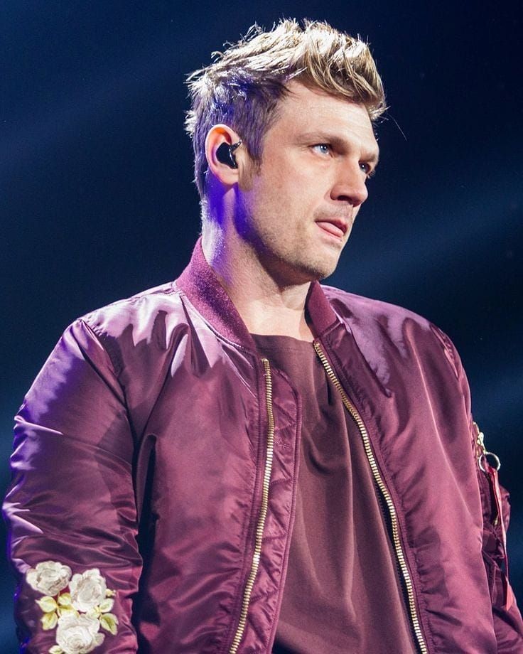 a man with ear buds on his ears is standing in front of a purple light