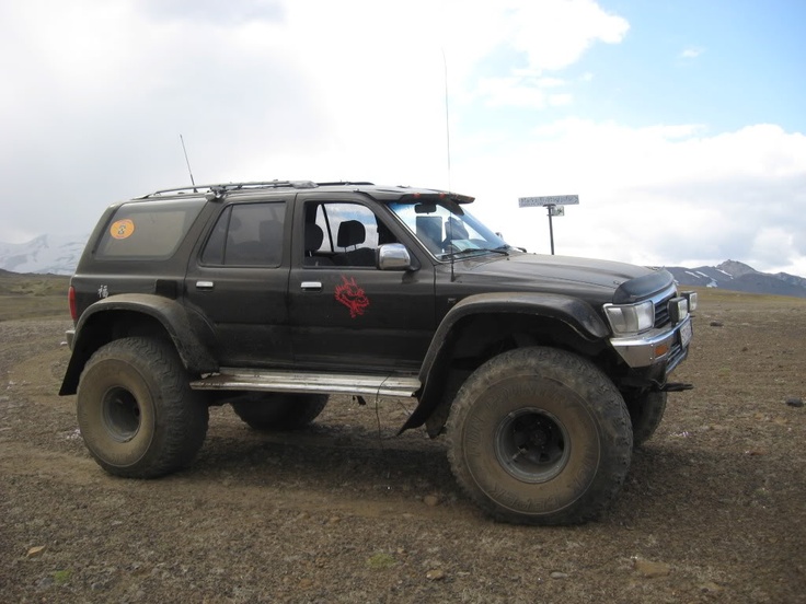 a large black truck parked on top of a dirt field