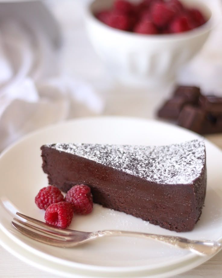 a piece of chocolate cake on a plate with raspberries