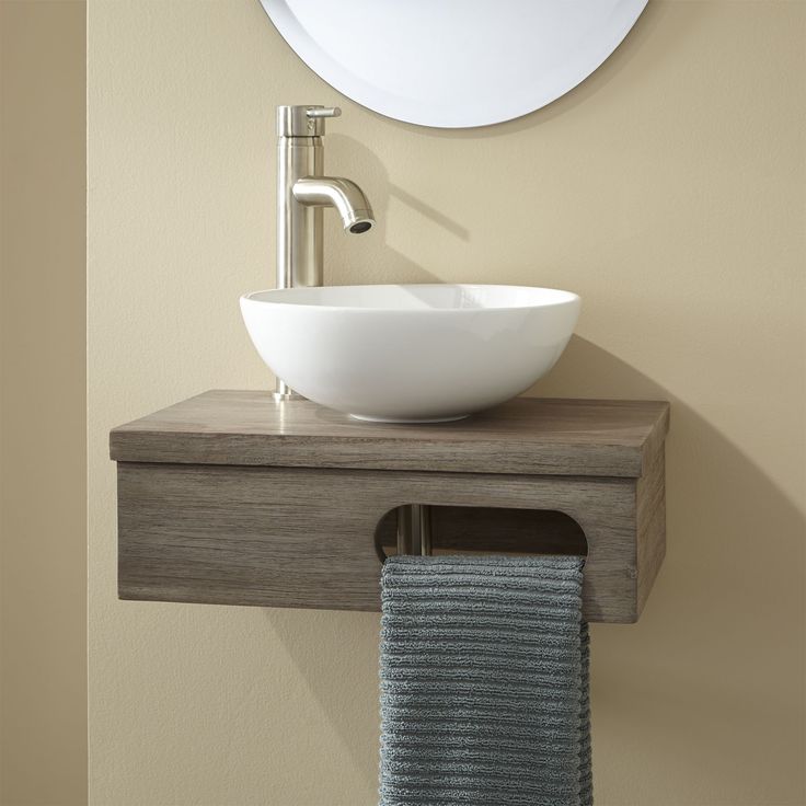 a bathroom sink sitting under a mirror next to a towel dispenser on a wall