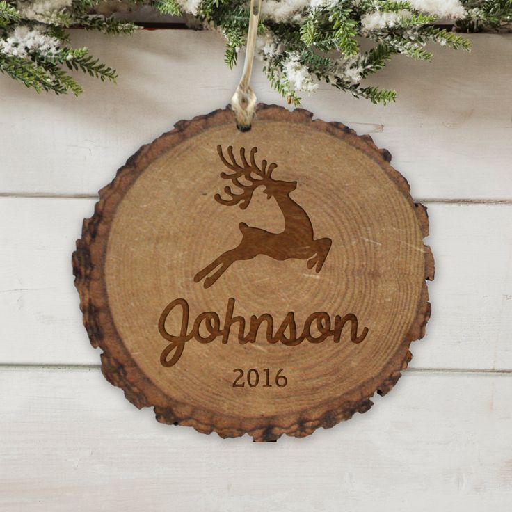 a personalized ornament hanging on a tree slice with evergreen branches in the background