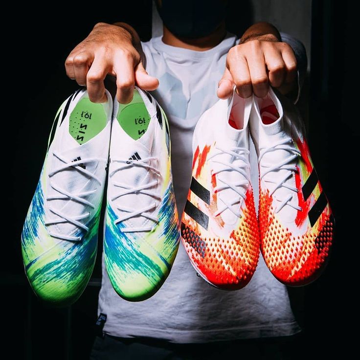 a person holding two soccer shoes in their hands