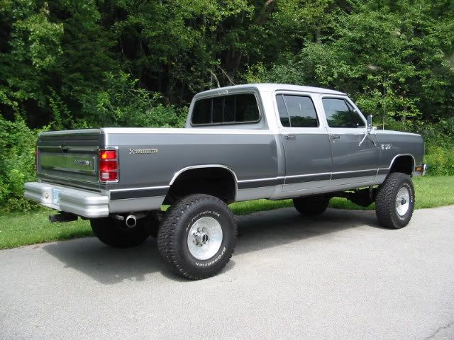 a gray pick up truck parked on the side of a road next to some trees