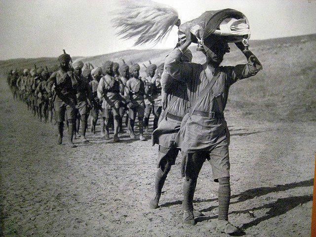 an old black and white photo of men walking in the desert