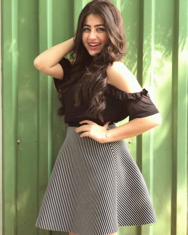 a woman standing in front of a green wall with her hands on her head and smiling