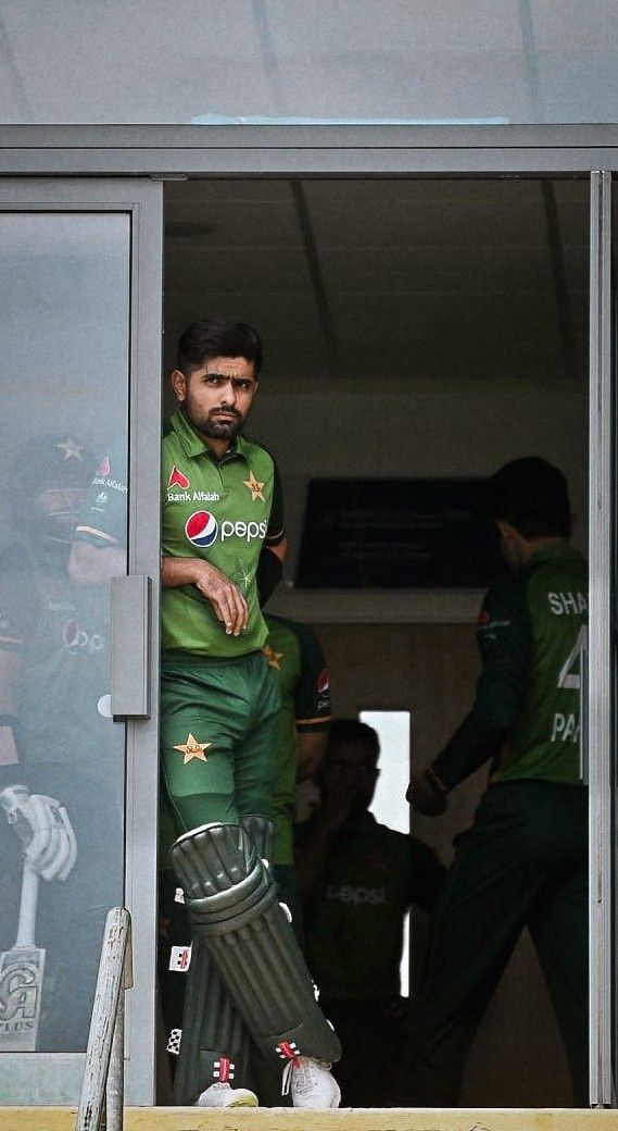 a man in green uniform standing on top of a window sill holding a bat