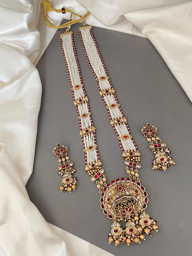 This Rajwadi Bandhai necklace is not just a piece of jewelry; it carries with it a rich heritage and cultural significance. With its timeless allure this necklace features layers of rice pearl piroyi with gold embellishments studded with colored stone tukdis, cluster & gold beads. Matching earrings included. Statement Jewelry. Perfect for any occasion.   WHAT GOES IN  👉🏻Copper Brass alloys. 👉🏻Necklace length: 26" & Drawstring Adjustable. ✅Check other styles available in our store https://www.etsy.com/shop/KKsCulture ✅ SHIPPING & TURNAROUND  👉🏻Please check item dispatch times before placing order. 👉🏻Please allow 1-2 business days for item to be dispatched. All shipments come with valid USPS tracking number.  👉🏻All pre / custom orders will take approximately 3 weeks. 👉🏻We use USP Rani Haar, Kundan Necklace Set, Gold Embellishment, Kundan Necklace, Colored Stone, Indian Wedding Jewelry, Kundan Necklaces, Jewelry Statement, Copper Brass