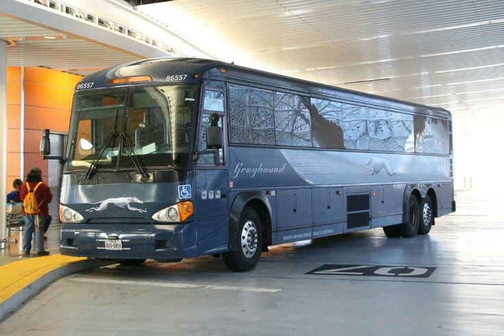 a blue bus parked in front of a building with people standing around it on the sidewalk