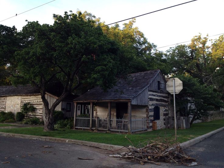 an old run down house sitting on the side of a road next to a tree