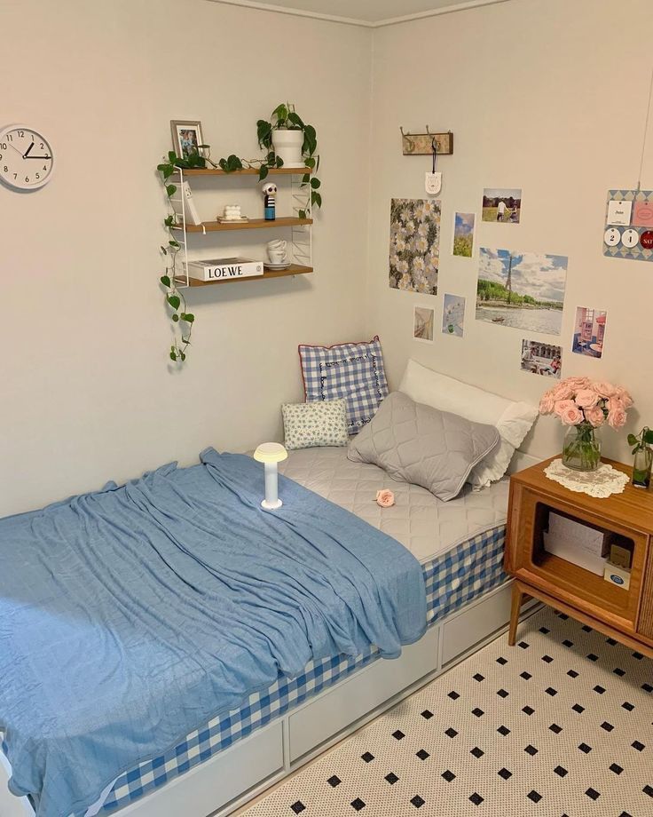 a small bedroom with a bed, desk and shelfs on the wall above it