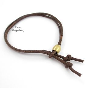 a brown cord with two gold beads on it