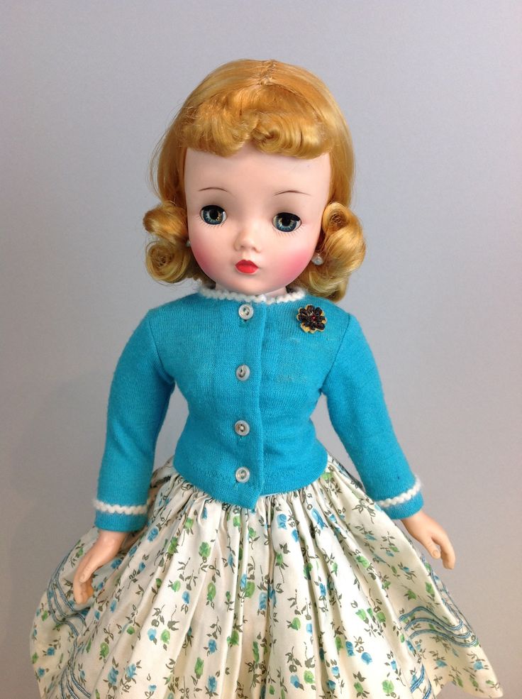 a doll with blonde hair wearing a blue jacket and dress