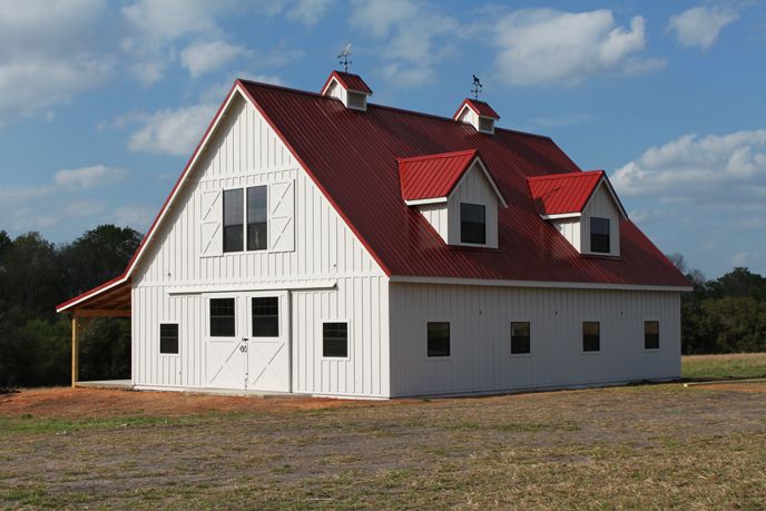 a large white barn with red roof and windows