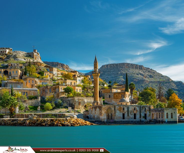 an island with many buildings on top of it near the water and mountains in the background