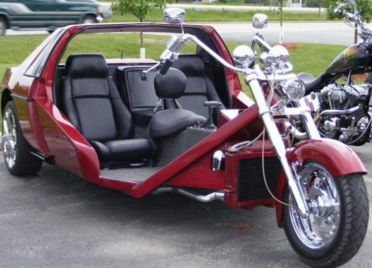 a red and black motorcycle parked in a parking lot next to a car with the door open