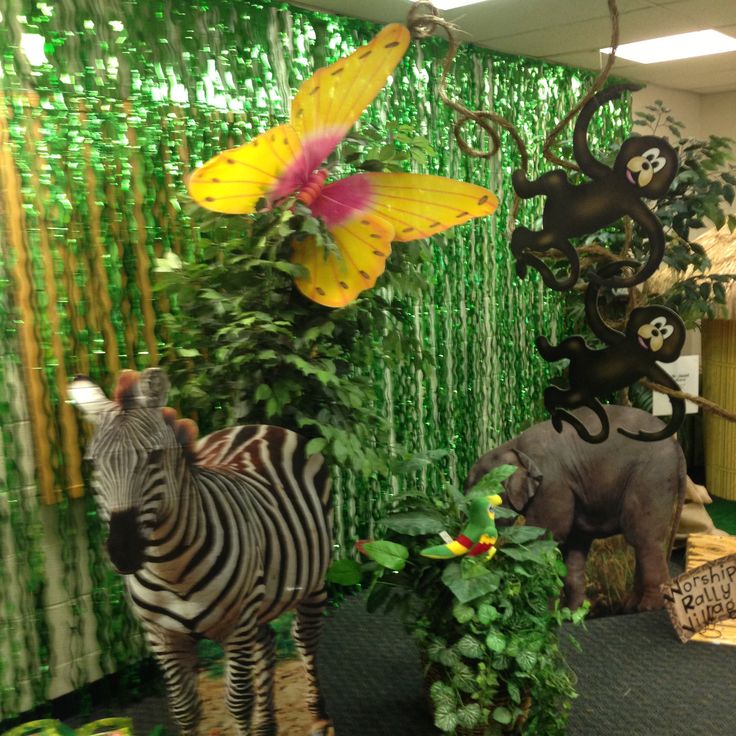 two zebras are standing next to each other in front of some fake plants and flowers