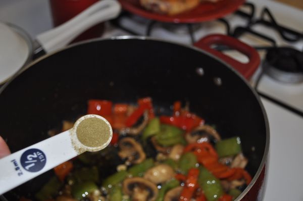 a person stirs vegetables in a wok on the stove with a spatula