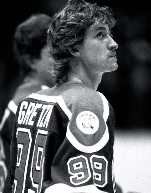 a hockey player is looking off to the side with his hands on his hips while standing in front of other players